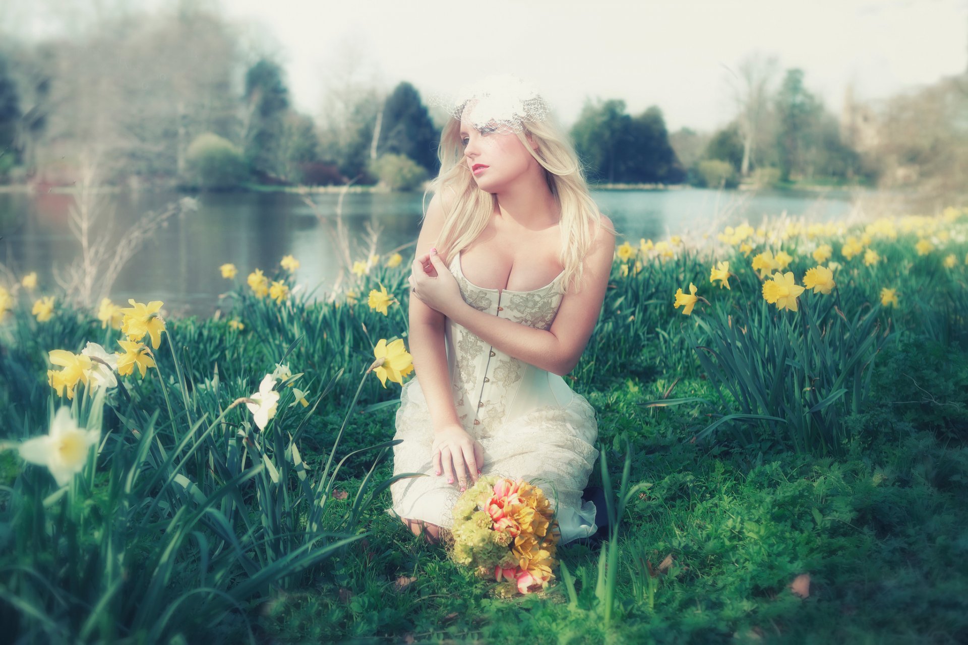 Голая блондинка с букетом цветов на берегу реки