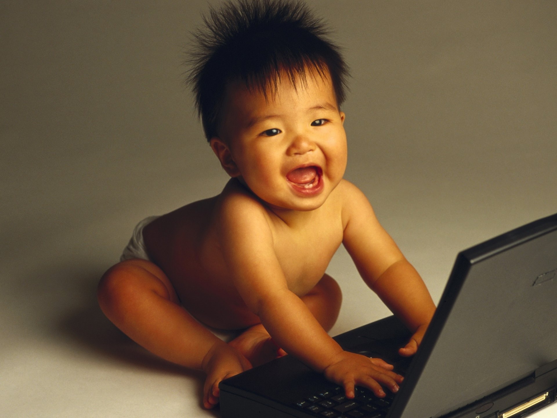 primi denti bambino ammirazione sguardo sorriso computer laptop asiatico briciola giochi scherzi fidget giocattolo delizia occhi viso