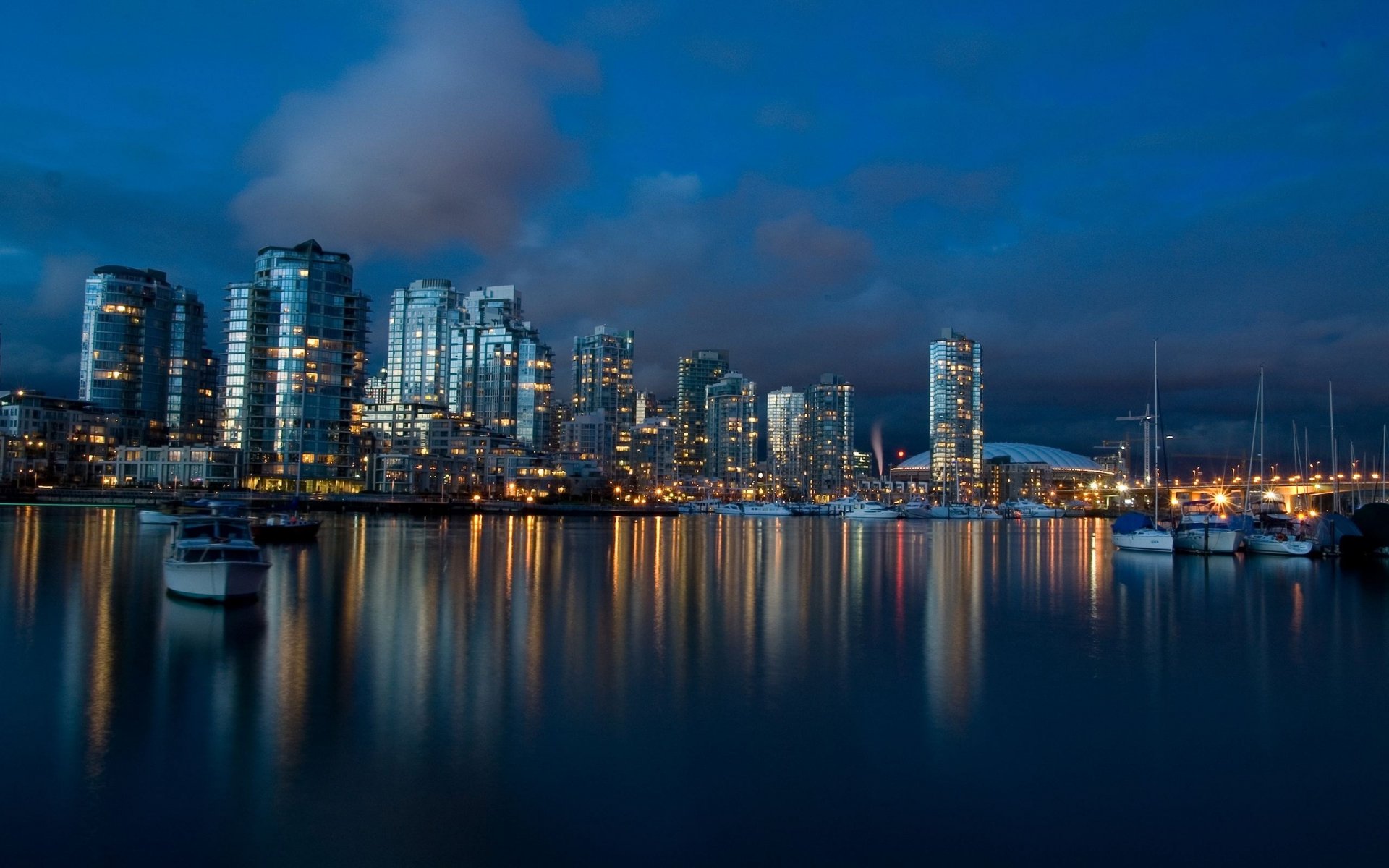 nachtansicht panorama stadt am wasser hochhäuser städte wolkenkratzer nacht nachthimmel lichter der städte wasser spiegel reflexion blau boot boote metropole ansicht