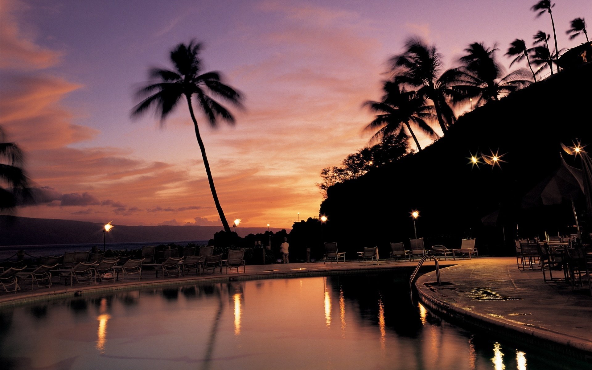 agua noche linternas tumbonas piscina puesta de sol palmeras cielo vacaciones hotel resort tumbonas siluetas sombra árboles trópicos cielo rosa luces reflexión
