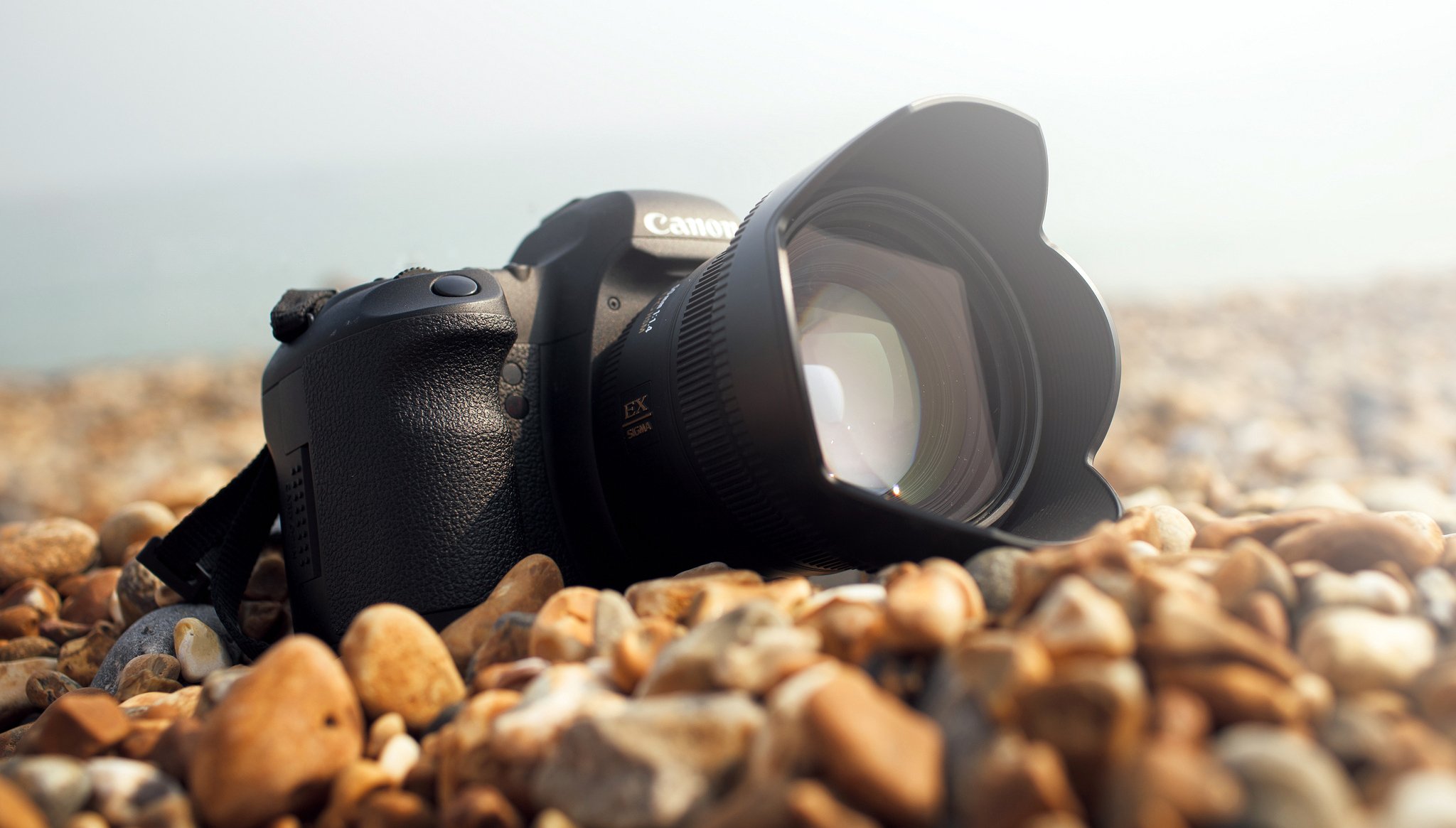 macchina fotografica canon lente pietre riva mare giornata di sole