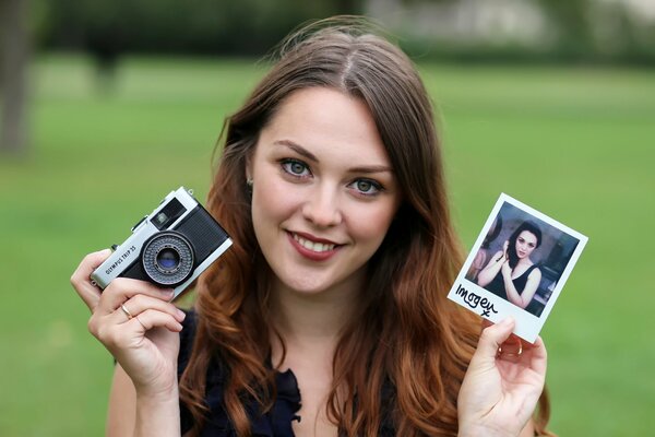 Una chica sonriente con una foto y una foto en sus manos