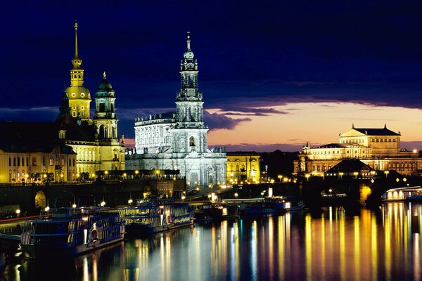 The towers and lights of the city are reflected in the night water