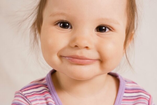 Petite fille souriante aux yeux bruns dans un t-shirt rayé