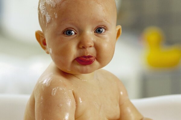 A small child is sitting in a bathtub in soap suds