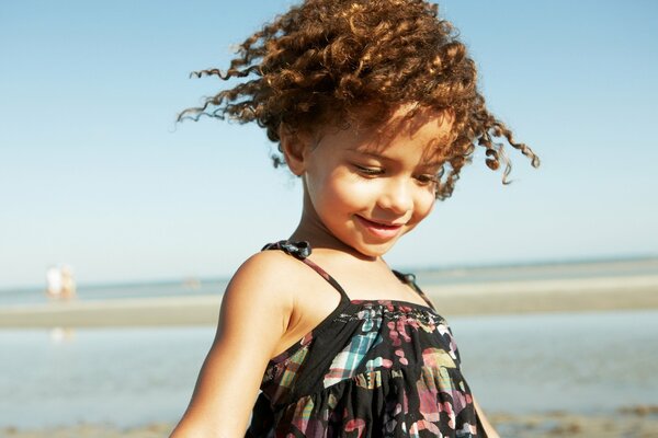 Ragazza con riccioli in riva al mare. Sorriso della ragazza