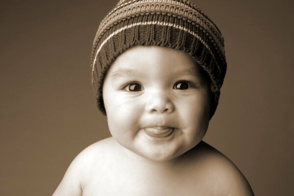 Petit enfant dans un chapeau montre la langue