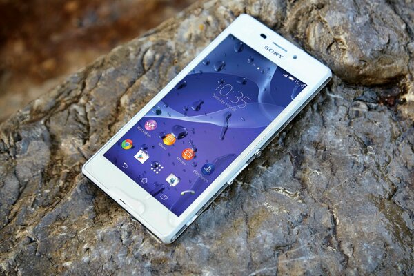 Sony s white smartphone is lying on a wet stone
