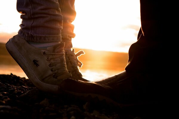 Two pairs of shoes - she and he on the background of the sunset