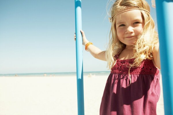 Lächelndes blondes Mädchen am sonnigen Strand