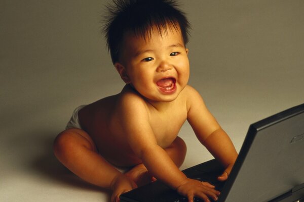 A small child is sitting next to a laptop