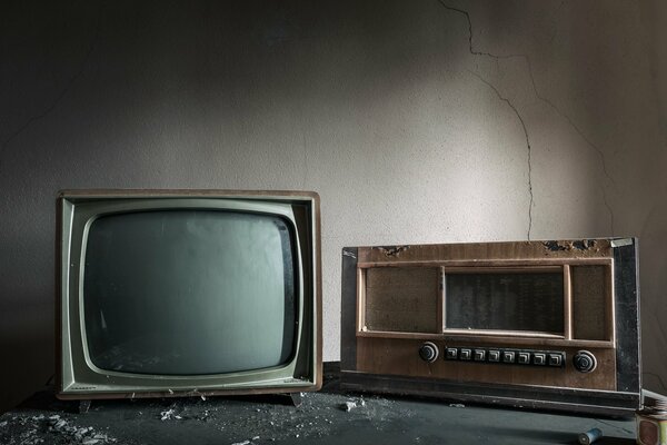 Vecchia TV e radio sullo sfondo di un muro incrinato