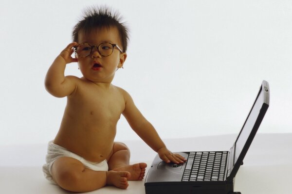 Ein kleines Kind mit Brille sitzt am Laptop