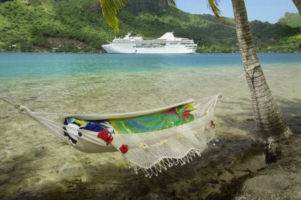 Hammock on the shore of the lake, a ship in the background
