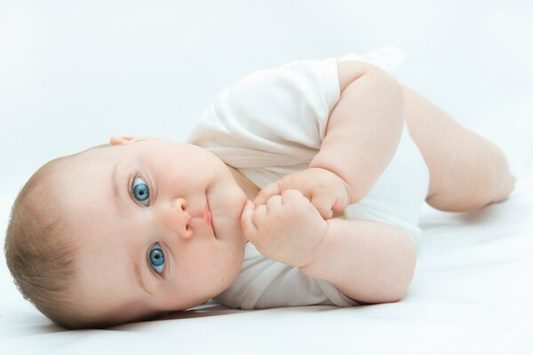 L enfant est allongé et regarde avec ses beaux yeux bleus