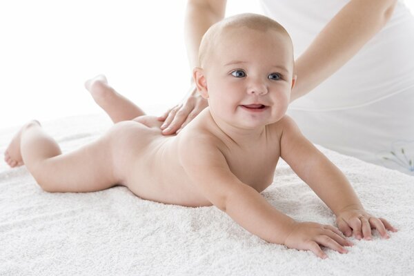 Das Baby liegt auf dem Bauch und lächelt glücklich