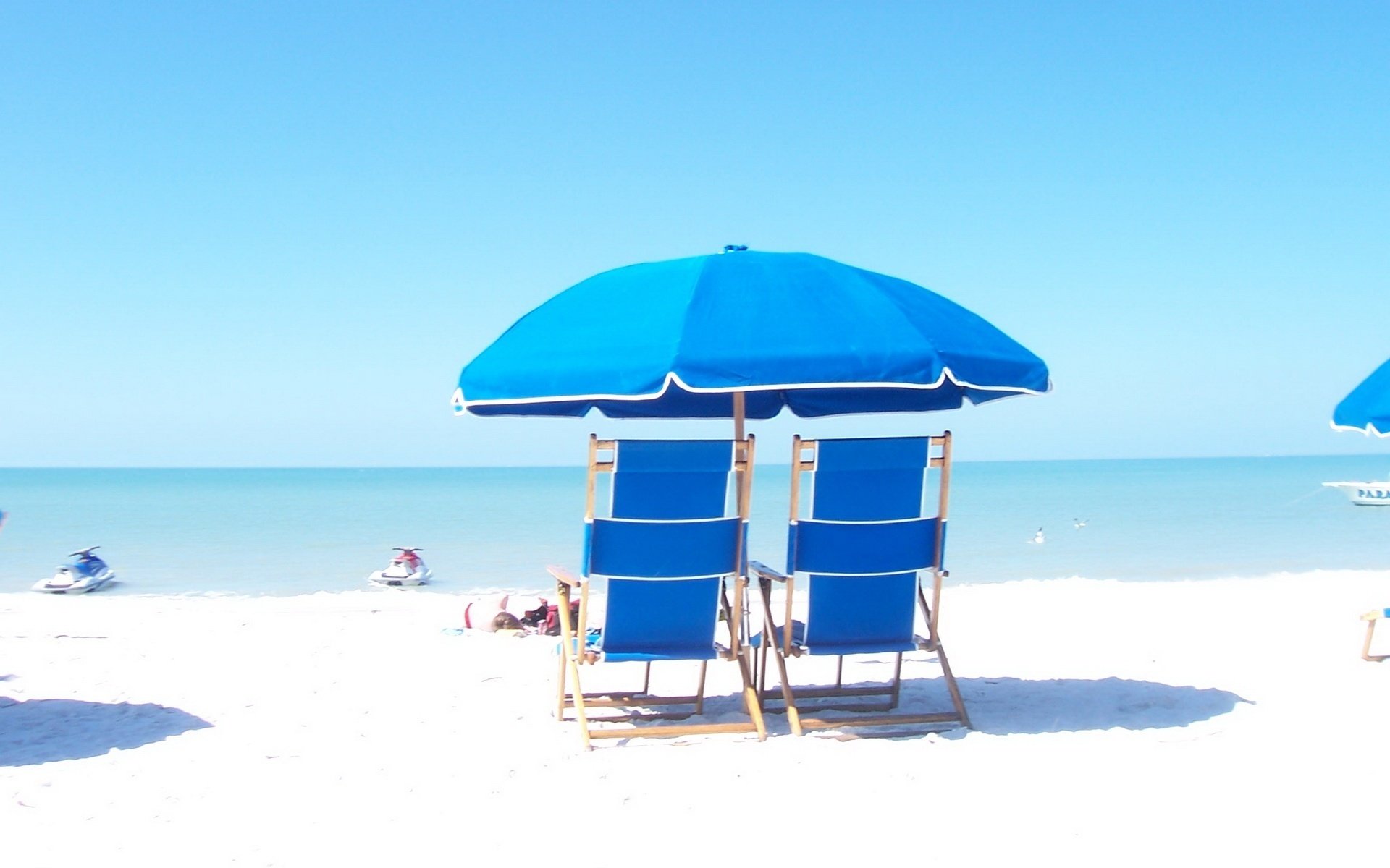 in blue tones couple sun beds umbrella beach deck chairs summer heat heat shore sea horizon vacation resort vacation boat