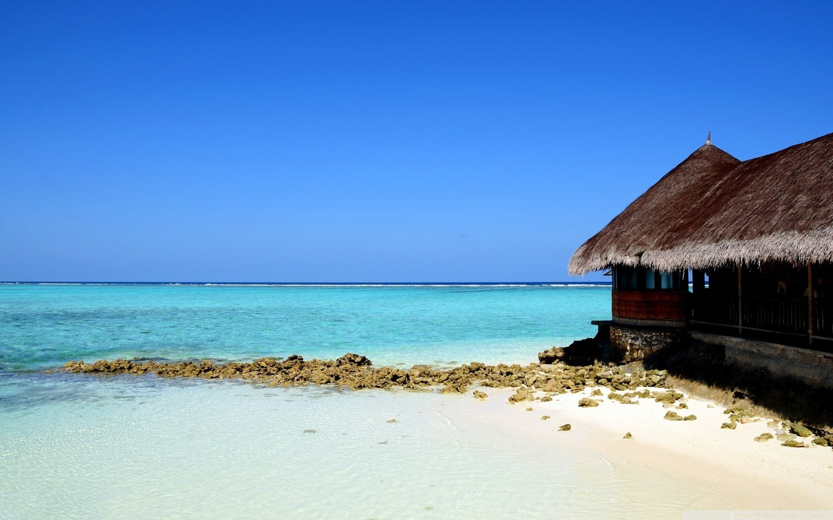 strohhaus am meer sand strand wasser himmel küste horizont erholung natur landschaft dächer steine azurblau klarer himmel sommer hitze hitze tropen paradies