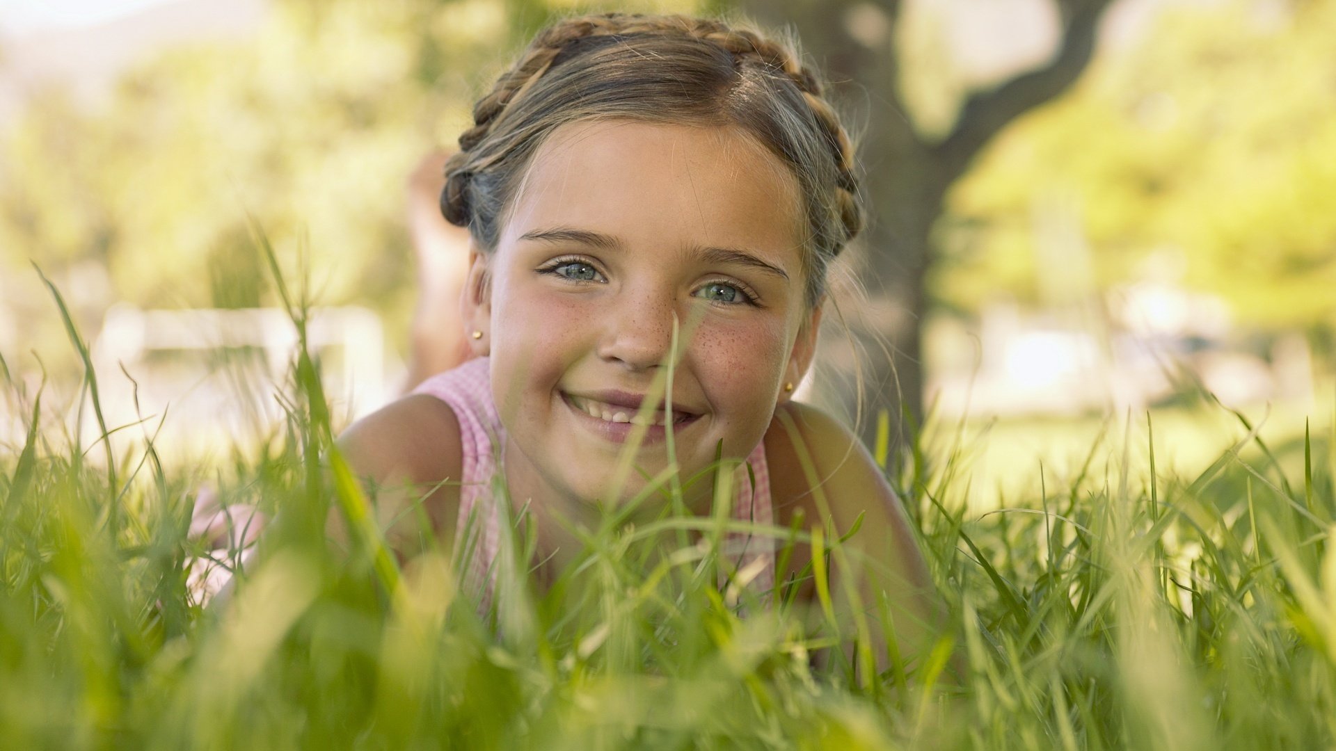 liegt im gras funkelnde augen mädchen charmantes lächeln porträt blick augen lächeln gesicht mädchen zöpfe frisur stimmung sommer grün freude emotionen sommersprossen