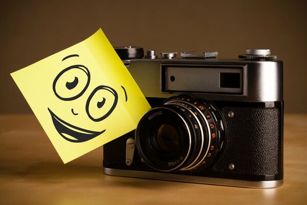 Macchina fotografica con smiley sorridente sul tavolo