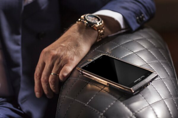 Orologio d oro sul braccio e smartphone