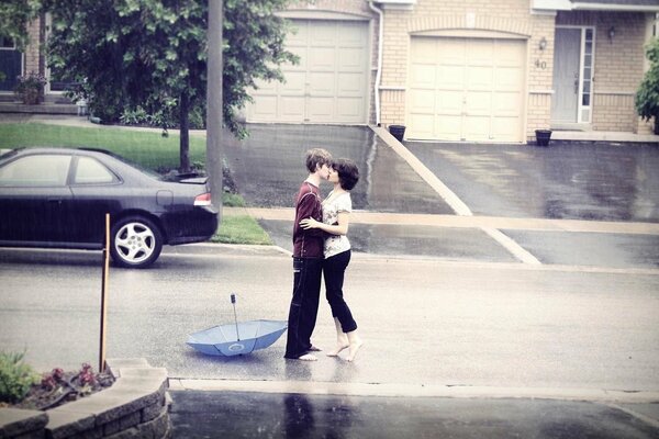 Chica y chico besándose suavemente bajo la lluvia