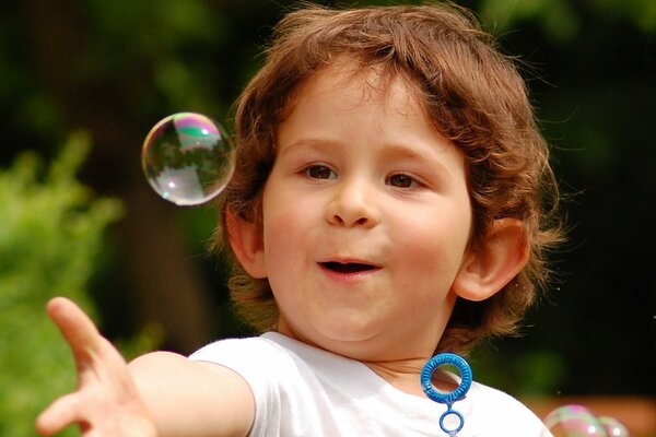 Garçon surpris joue avec des bulles de savon