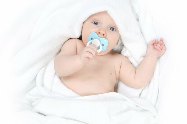 Bébé avec un mamelon dans la bouche dans une couverture blanche