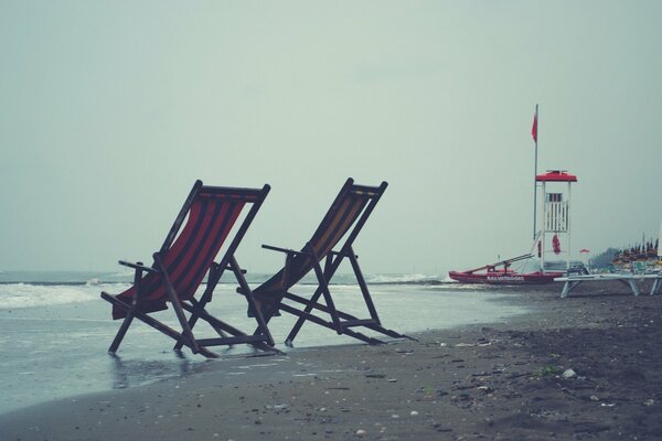 Liegestühle an einem grauen, bewölkten Strand