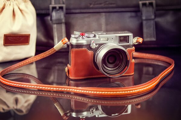 A small camera on a transparent table with an orange strap