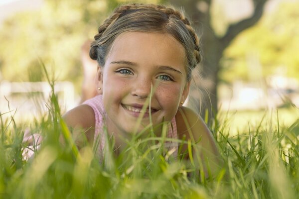 Una niña con una sonrisa encantadora yace en la hierba