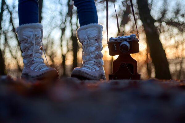 Jambes avec appareil photo sur fond de coucher de soleil