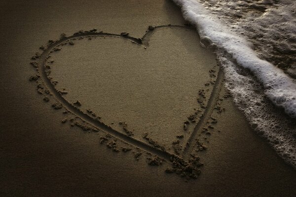 Malowane na piasku serce blisko morza