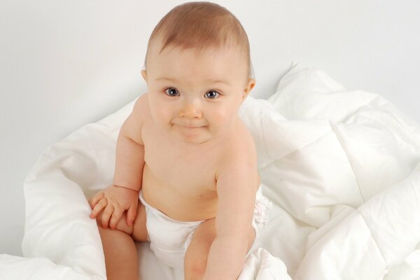 Bébé mignon sur une couverture blanche en couches