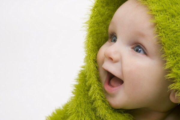 Bebé alegre sonriente en una colcha verde