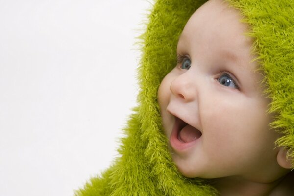 Sourire joyeux bébé dans un couvre-lit vert