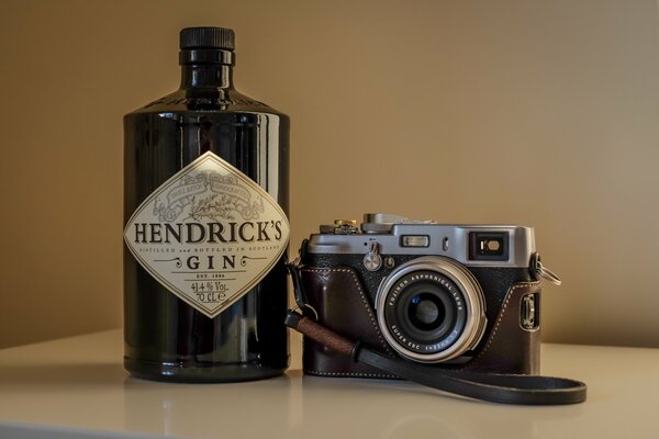 Kamera im Koffer auf dem Hintergrund einer Flasche Gin