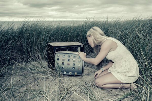 Das Mädchen im Gras öffnet das Keneskop des Fernsehers