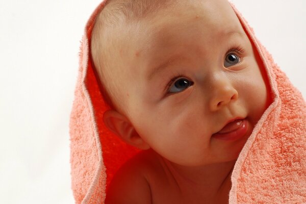 A smiling child in a pink terry towel