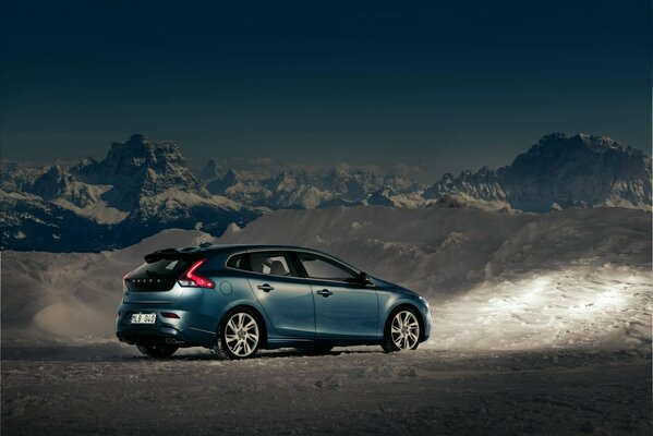 Volvo car among mountains and snow at dusk