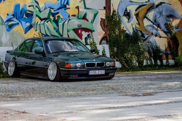 BMW E38 classica scura su sfondo di graffiti