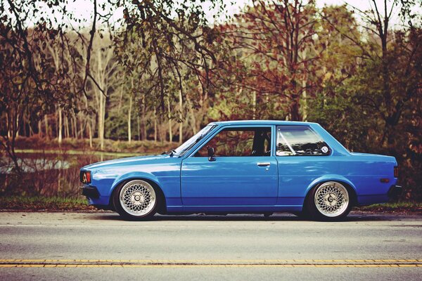 A blue Toyota is standing on the side of the road