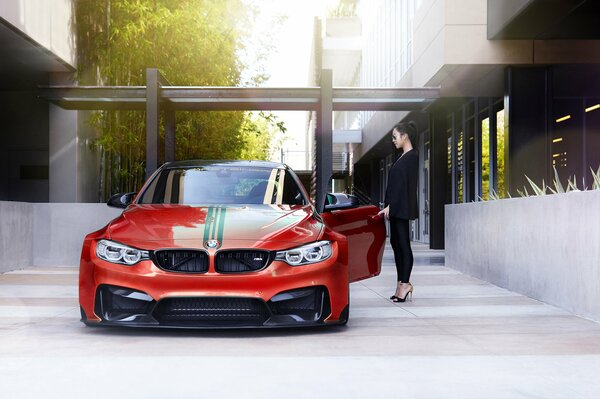 El coche rojo de bmw junto a la que se encuentra la chica de negro