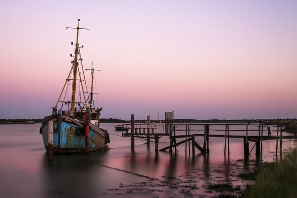 An old boat sails to the pier