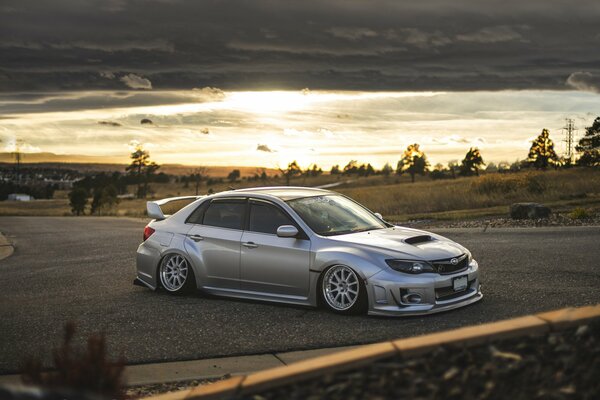 A silver subaru car is on the road