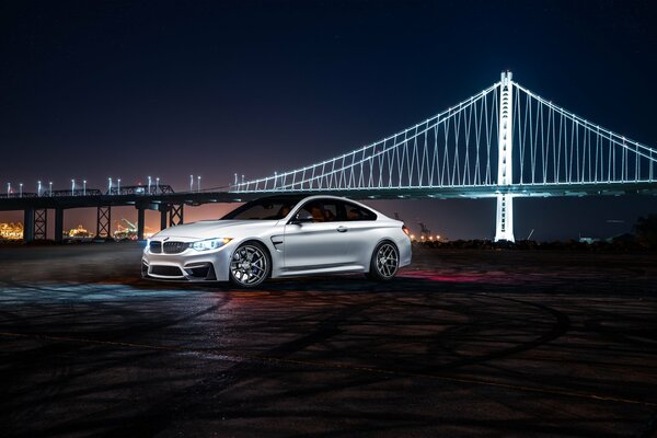 White BMW at night on the background of a white bridge