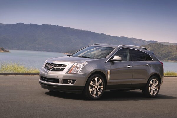 Cadillac srx SUV gris en el fondo de las montañas