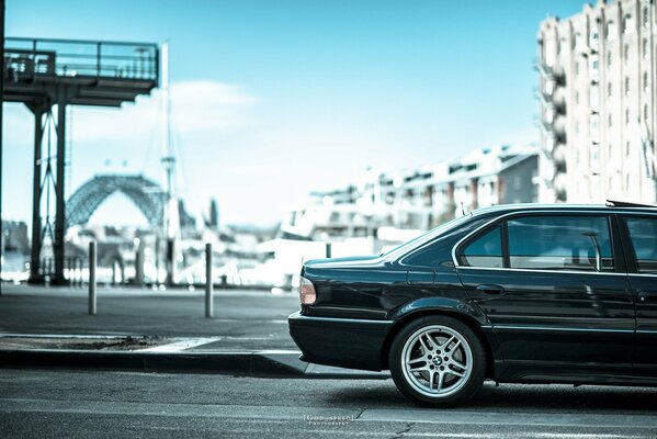 BMW e38 740il черная стоит на дороге вид сбоку задняя половина