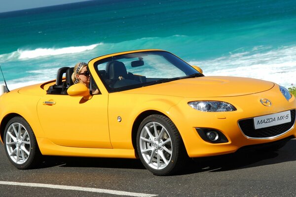 Mazda amarillo brillante contra las olas del mar