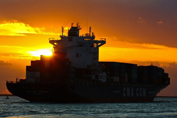 Navire porte-conteneurs sur fond de coucher de soleil